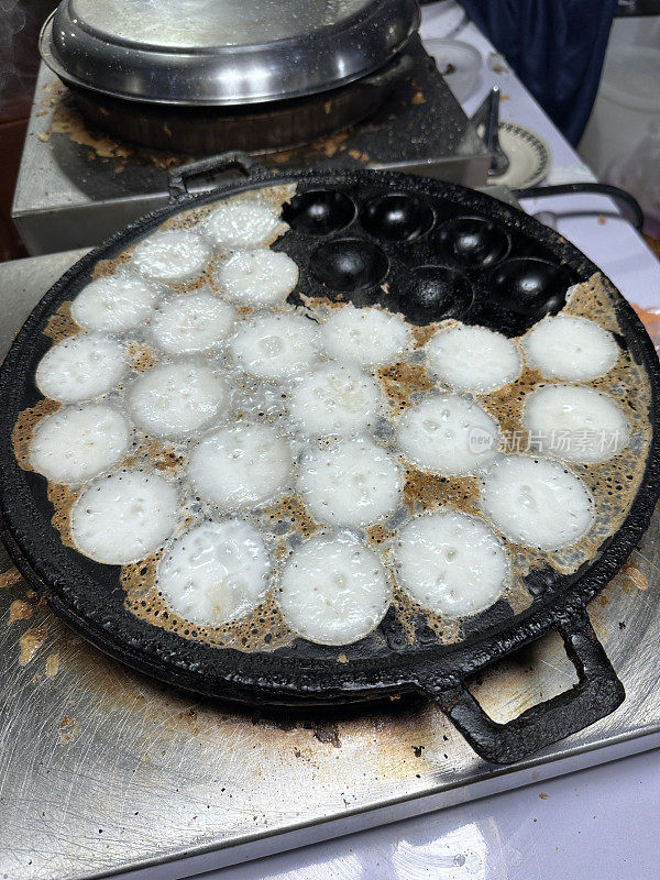 泰国椰子煎饼(Kanom Krok)的特写图像甜，街头小吃正在铸铁Ebelskiver风格的锅，高架视图，重点在前景